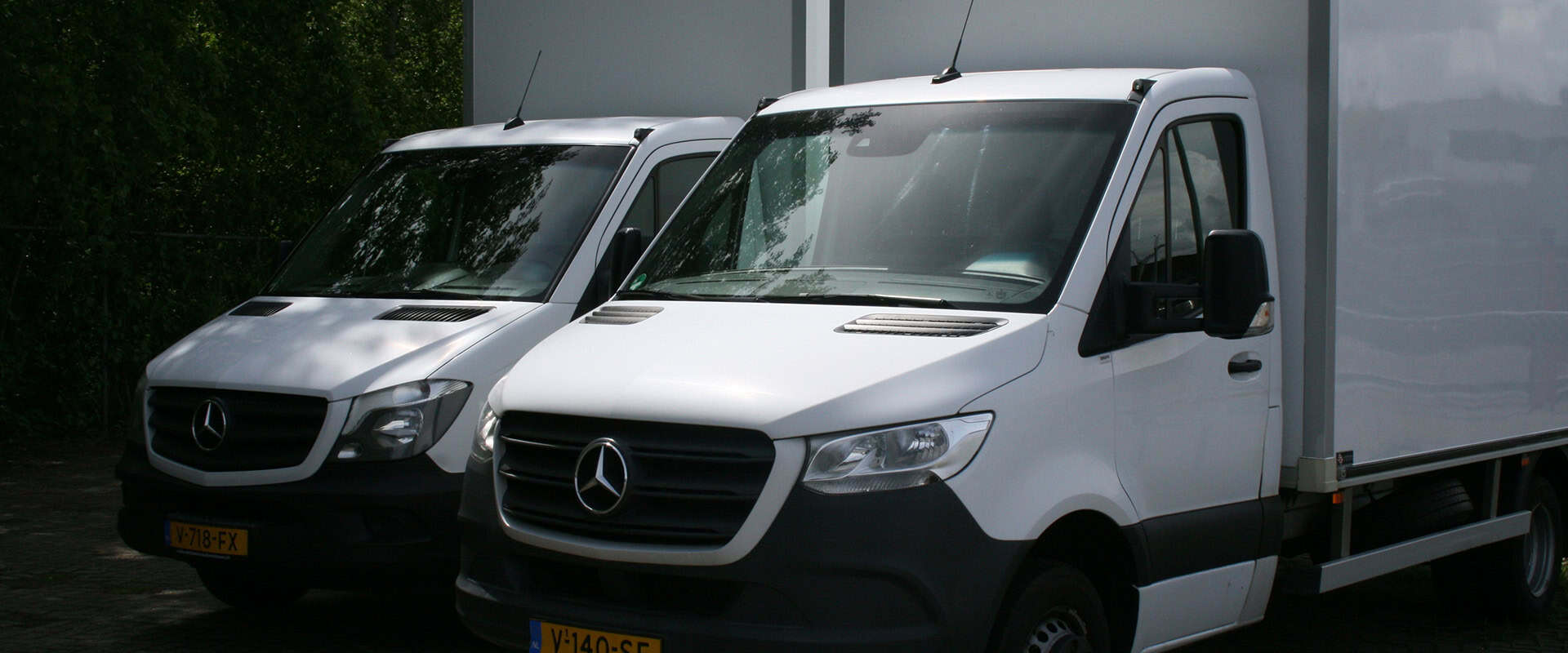 Twee witte Mercedes-Benz bestelwagens naast elkaar geparkeerd
