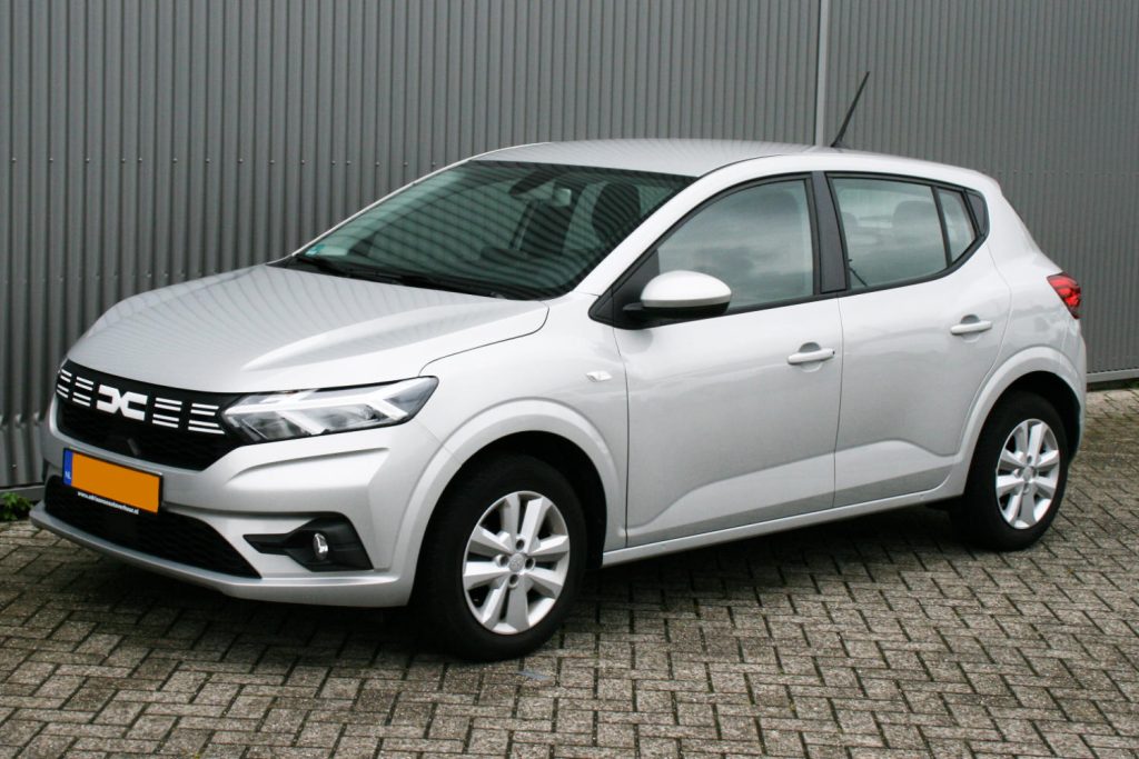 Zilveren Dacia Sandero hatchback geparkeerd voor grijze gevel