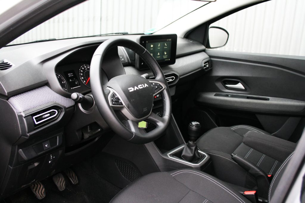 Interieur van Dacia met stuur, touchscreen en handgeschakelde versnellingsbak