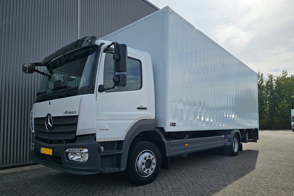 Witte Mercedes-Benz Atego bakwagen naast bedrijfshal