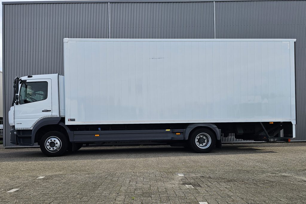 Witte gesloten bakwagen naast grijze bedrijfshal