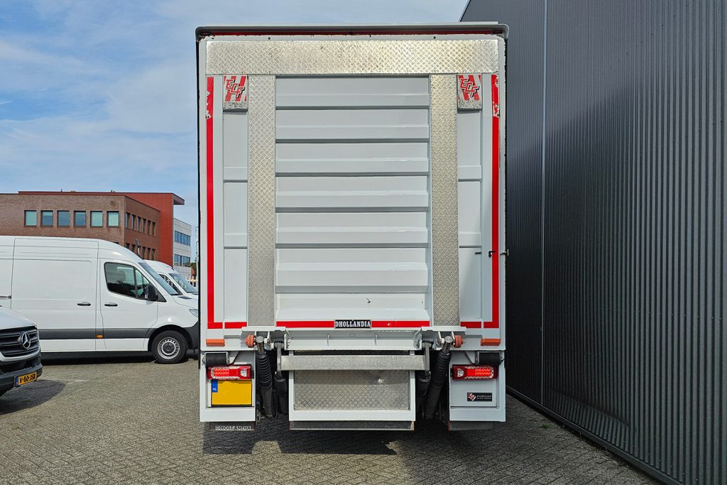 Achterzijde vrachtwagen met gesloten laadklep op bedrijfsterrein