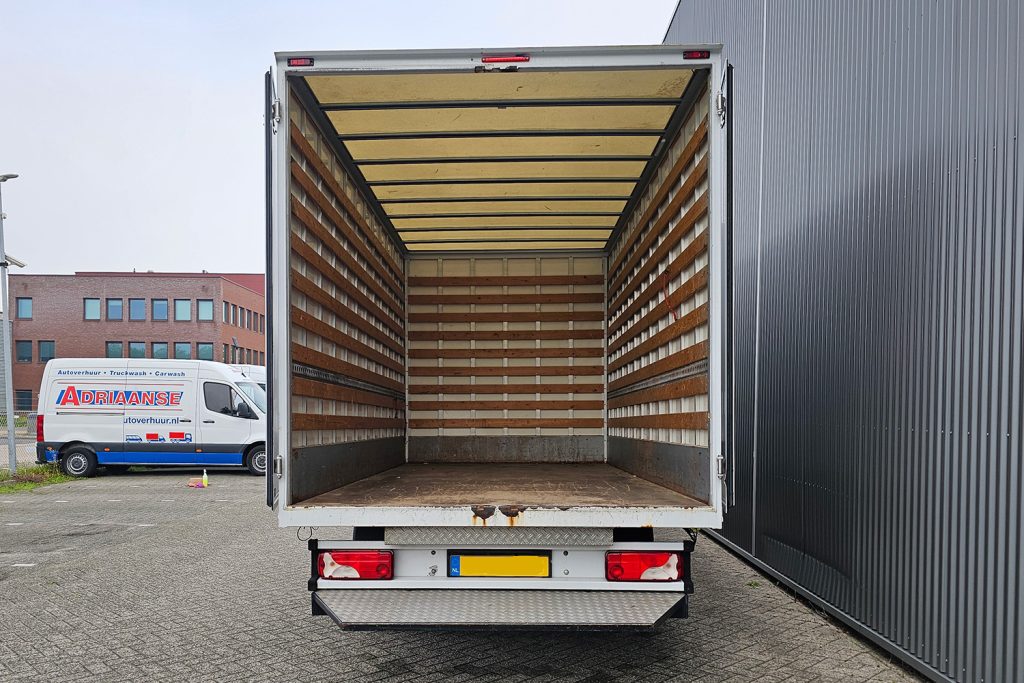 Open lege verhuiswagen bij bedrijfsgebouw