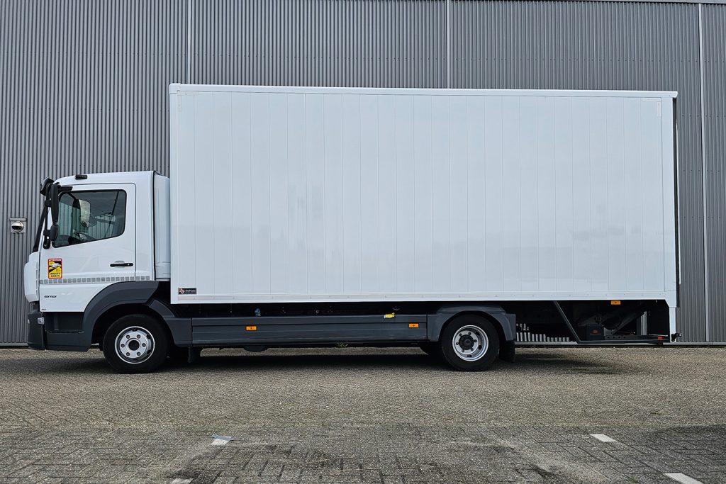 Witte bakwagen geparkeerd voor grijze metalen gevel