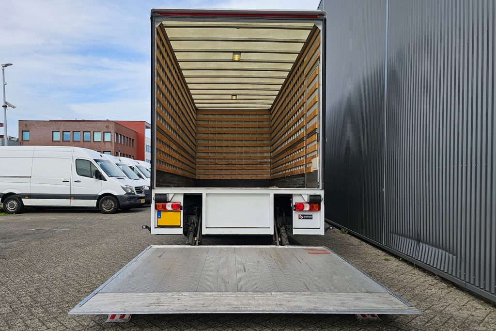 Lege verhuiswagen met neergelaten laadklep op bedrijfsterrein
