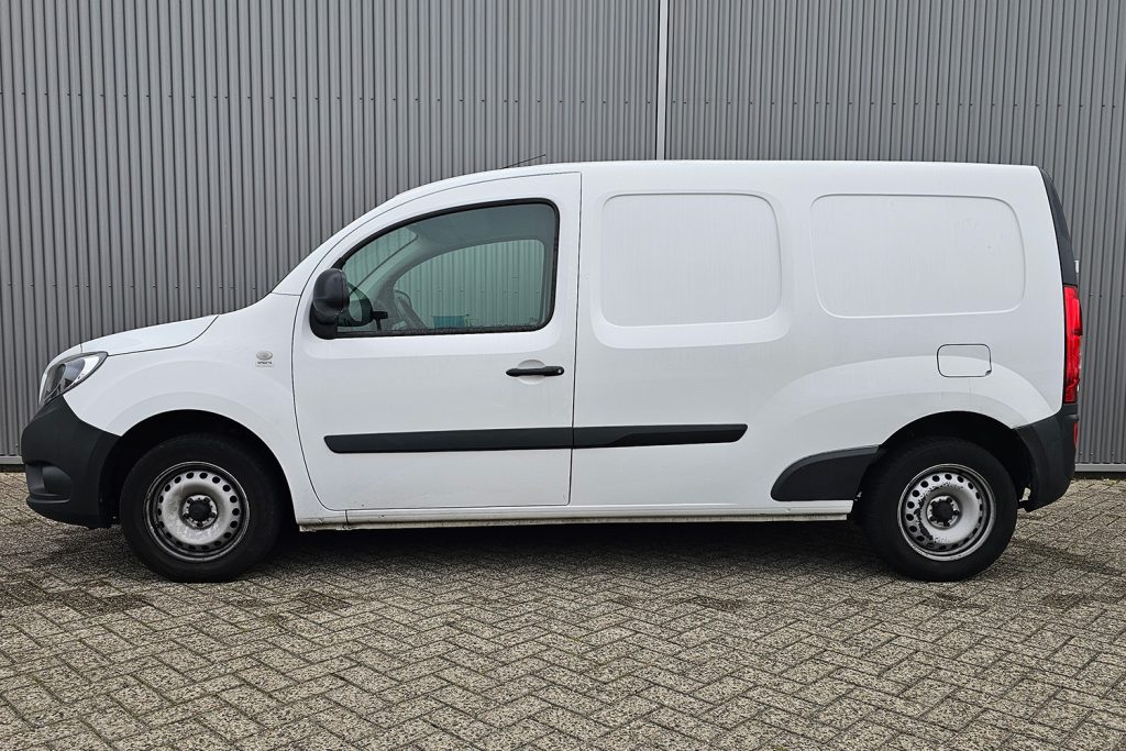 Witte gesloten bestelwagen naast grijze metalen wand
