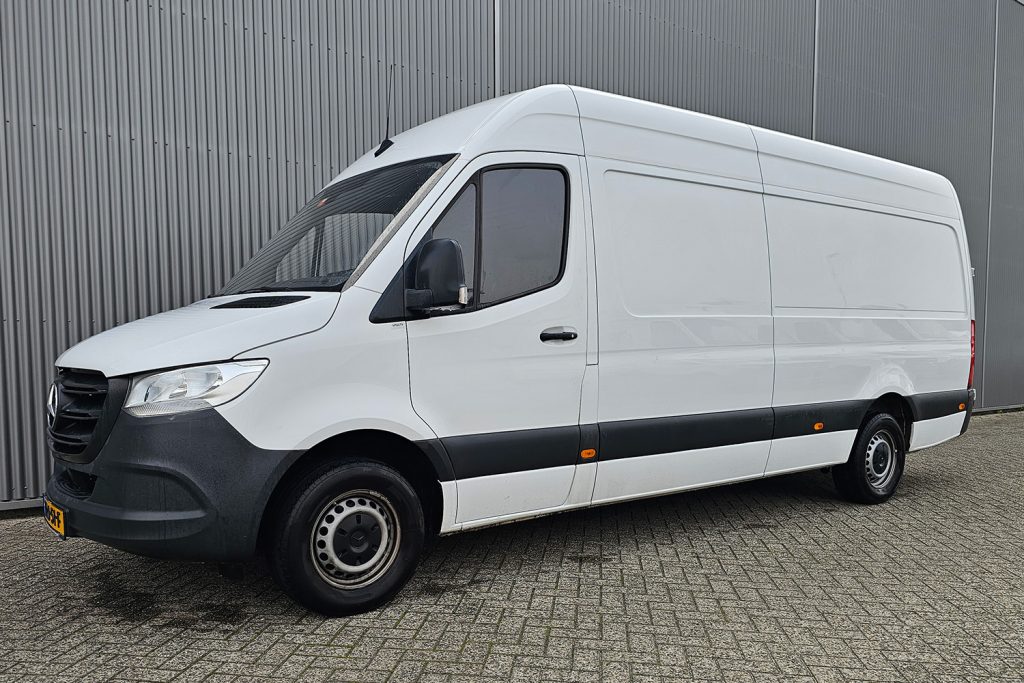 Witte Mercedes-Benz bestelbus naast grijze metalen wand
