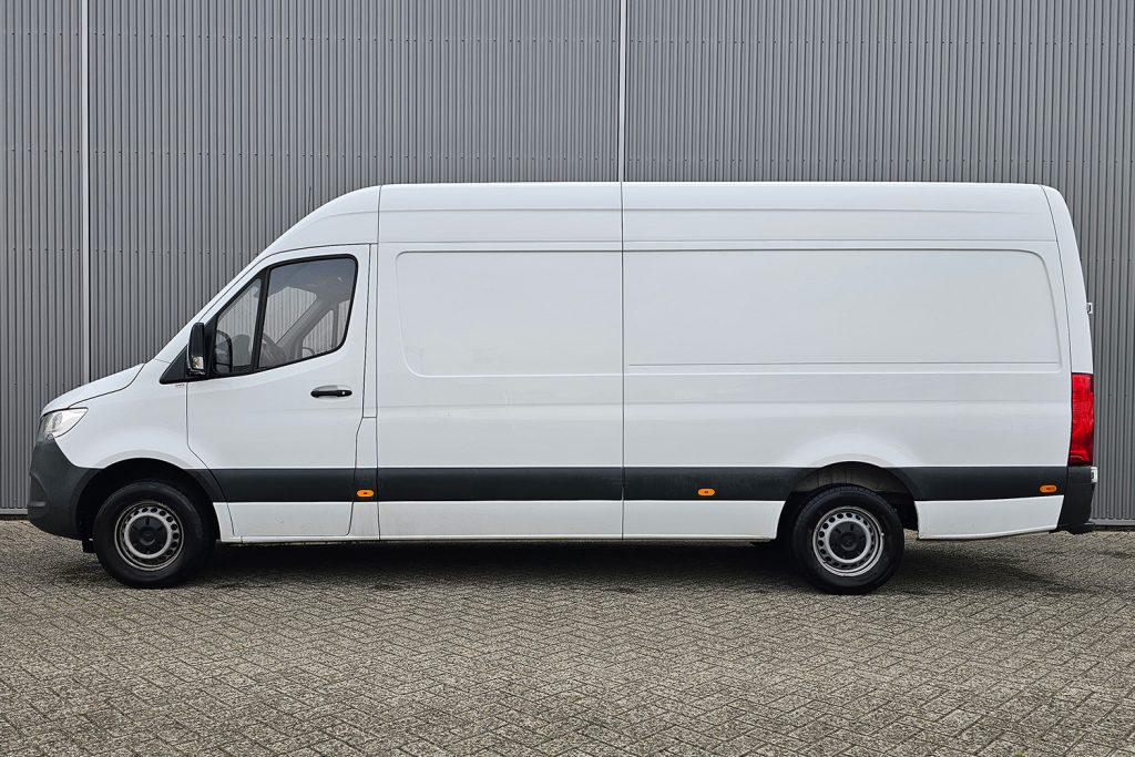 Witte gesloten bestelbus geparkeerd voor grijze metalen wand
