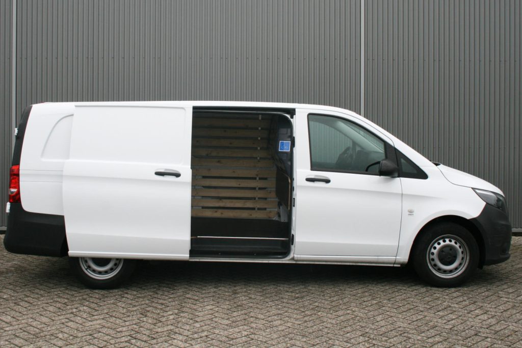 Witte bestelbus met open schuifdeur en houten laadruimte