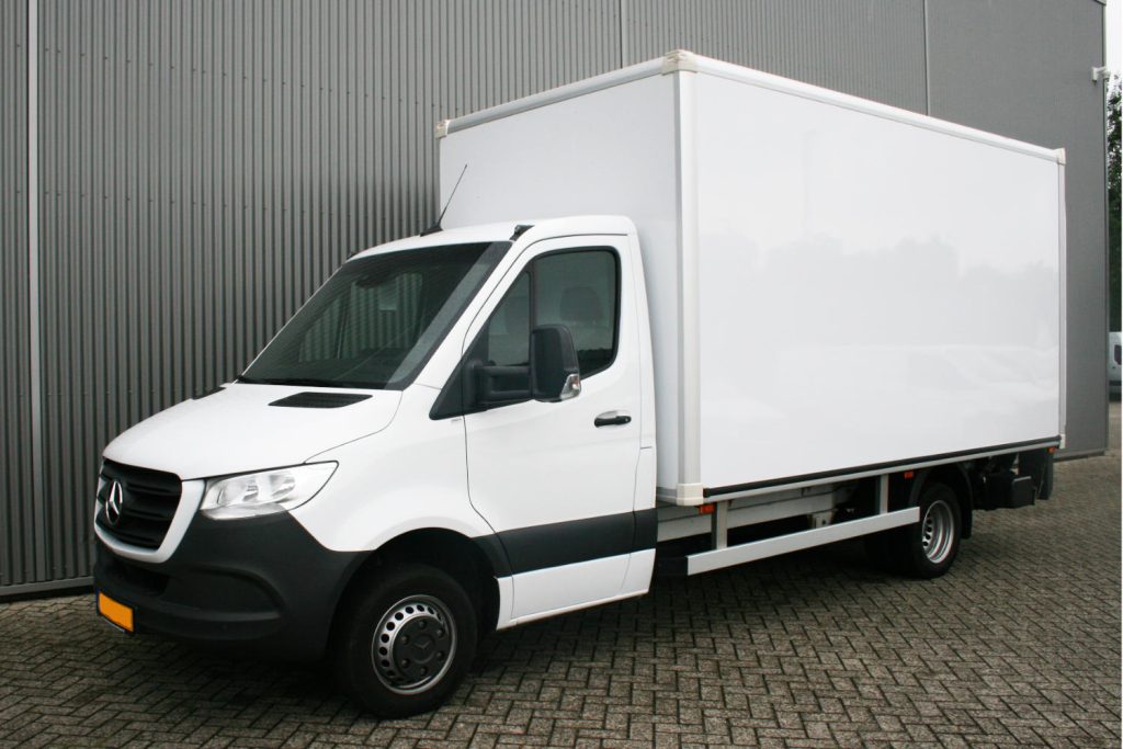 Witte Mercedes bestelwagen met gesloten laadbak bij loods