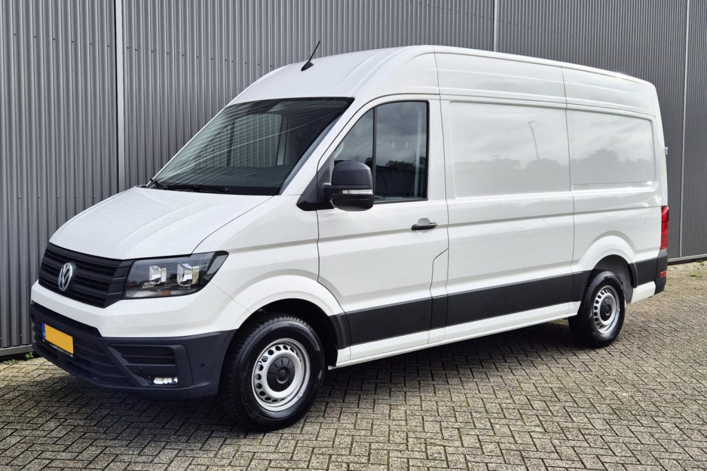 Witte Volkswagen Crafter bestelbus geparkeerd bij metalen wand