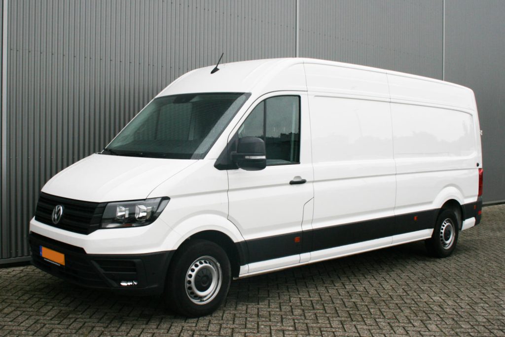 Witte Volkswagen bestelbus geparkeerd voor metalen gevel