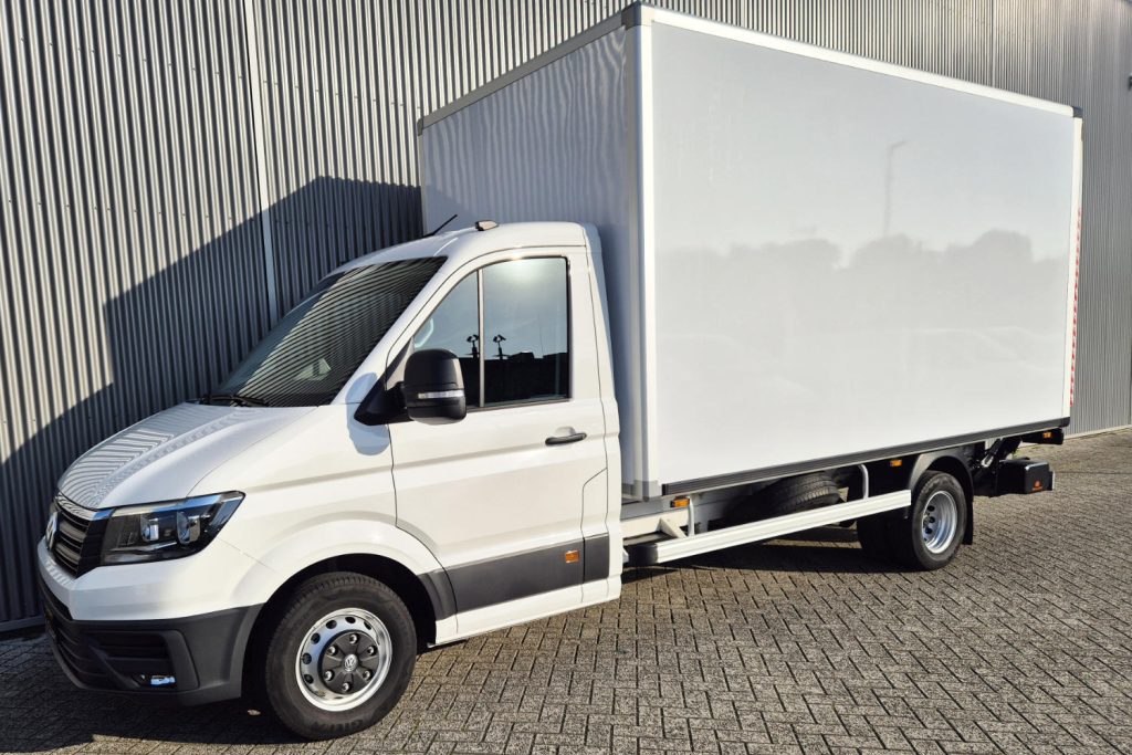 Witte bakwagen geparkeerd naast een metalen bedrijfsgebouw