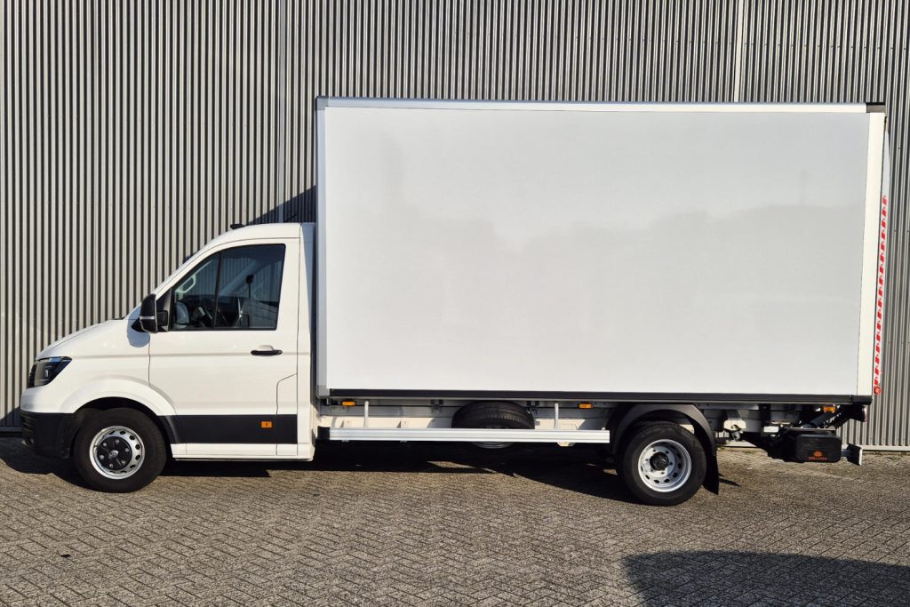 Witte bakwagen geparkeerd voor een metalen gevel